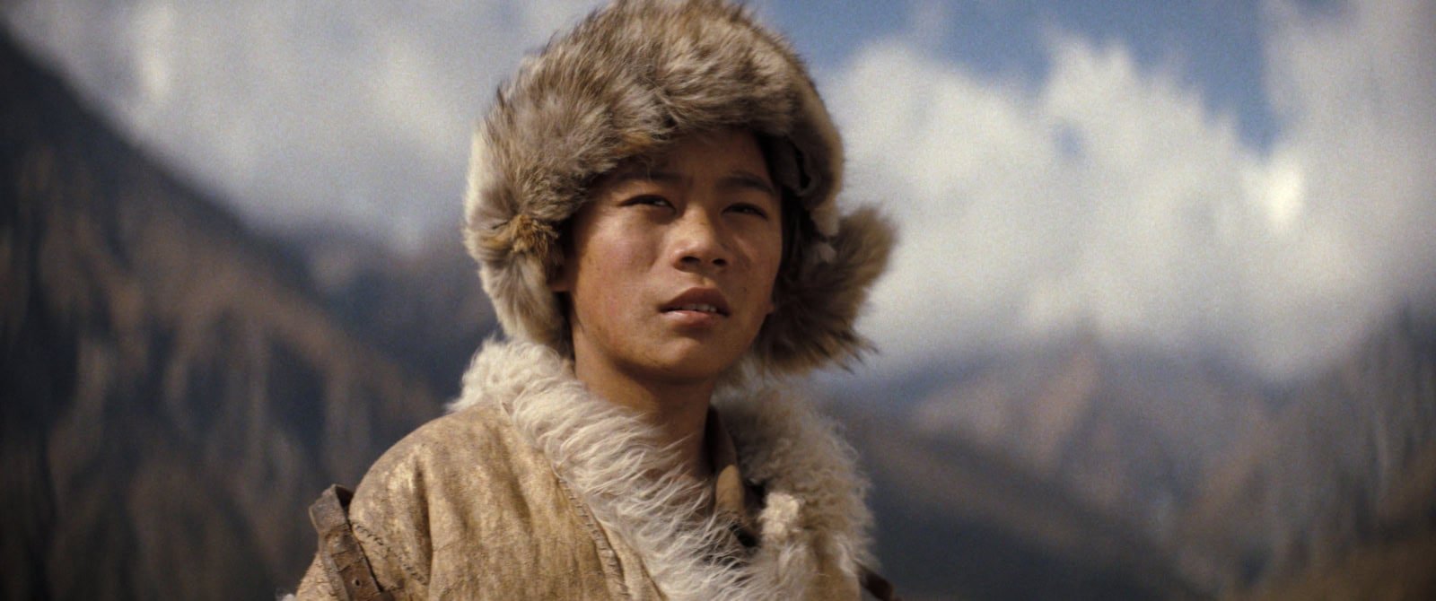 Il giovane Tenzing Norgay, interpretato da Genden Phuntsok, con il colbacco di pelliccia guarda verso le montagne dell'Himalaya